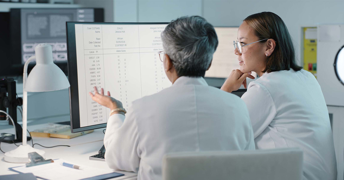 
  Healthcare workers looking at a spreadsheet on a computer monitor
