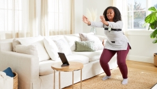 A woman wearing Hinge sensors performing exercises guided via a tablet