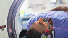 
  Person being rolled into an imaging machine with red lasers scanning their head 
