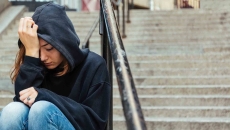 Person sitting on steps with their head in their hand