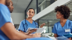 Four people in nursing uniforms, one wearing stethoscope