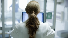 
  Healthcare provider with their back turned while looking at a computer
