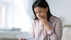 
  Person with their mouth covered looking at a piece of paper
