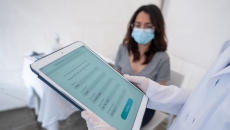 
  Healthcare provider on a tablet with a patient sitting in a room
