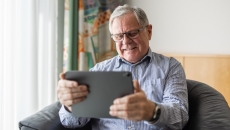 Person sitting in a chair while looking at a tablet