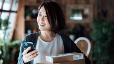 Person smiling while in their home and holding a phone with boxes around them