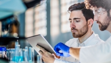 Two scientists in a lab looking at a tablet