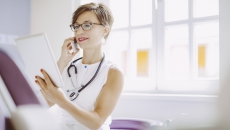 Healthcare provider with a stethoscope around their neck while holding a tablet