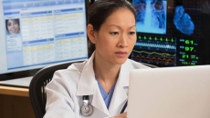 Healthcare professional sitting at a desk with many computers around them