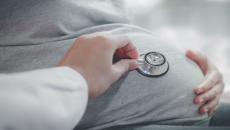 Healthcare provider listening to a person's stomach using a stethoscope