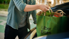 
  Person putting a bag of groceries from Uber Eats in a car's trunk
