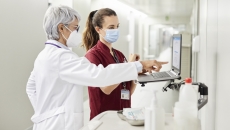 
  A doctor and a nurse using a laptop in a hospital.
