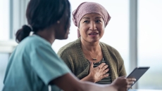 Oncology patient sitting next to a healthcare provider while looking at a tablet