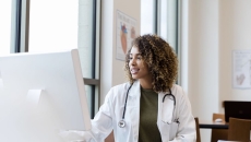 
  Healthcare provider with a lab coat on sitting at a desk and looking at a computer
