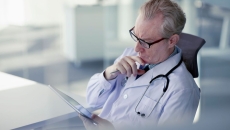 
  Physician sitting in a chair looking at a tablet
