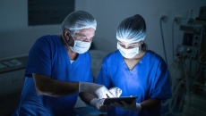 Two healthcare providers consulting a tablet in the operating room