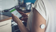 Person with a continuous glucose monitor checks their health data on a smartphone app