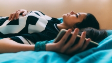 Person lying on a bed while holding a phone