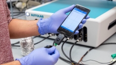 Penn researcher holding a smartphone as it uses the RAPID test to detect COVID-19
