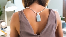 Person wearing the Upright GO S on the necklace while working at a desk