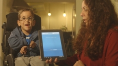 Boy in a wheelchair uses Voiceitt with the help of a caregiver