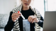 A person at home puts a lab sample into a bag for shipping