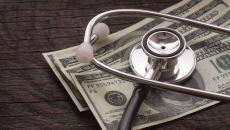 A stethoscope rests on dollar bills