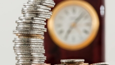 Silver and gold coins with a clock in the background.