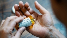 Person holding a pill bottle and pouring medication into their hand