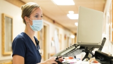 Healthcare worker in mask working on a laptop