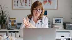 Healthcare professional sitting at a desk looking at a computer