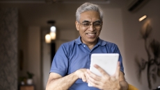 Person in a blue shirt holding a tablet while smiling and looking at the device