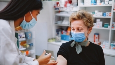 Person sitting in a pharmacy and getting an injection by a pharmacist