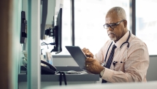 Healthcare provider sitting at a desk and looking at a tablet