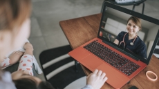 Two people sitting down while looking at a computer with a healthcare provider on the screen