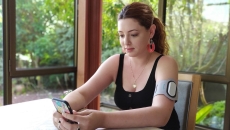 A person wearing an armband with the Theranica device while holding a smartphone.