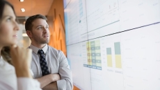 Businesspeople looking at financial results on a screen.