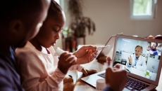 A father and daughter talking to a provider using a laptop