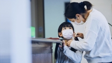 A mom checks a child's temperature before he goes to school
