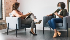 While wearing protective face coverings, a therapy patient and therapist discuss something.