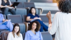 Students in scrubs sitting in a classroom looking at a teacher
