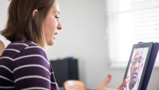 Person sitting down while looking at a computer with a telehealth provider on the screen