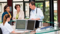 Healthcare providers in a clinic standing around a desk talking to each other