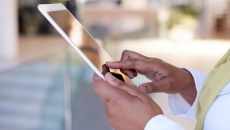 Person's hands holding a tablet while wearing a yellow scarf