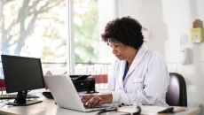 Healthcare provider sitting in an office at a desk with a computer on it