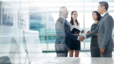 People standing in a room in front of a window while shaking hands