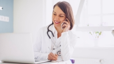 A doctor on the phone while checking a patient's record on a laptop computer