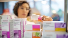 A pharmacist checking medicines on a rack