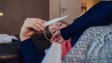 A sick woman looking a thermometer