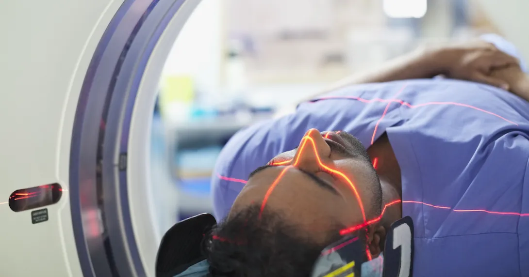 Person being rolled into a diagnostic imaging machine with lasers scanning their body